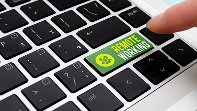 Close-up of a laptop keyboard with a finger pressing a green 'REMOTE WORKING' key, featuring an icon of three people, positioned where the Enter key is typically located.